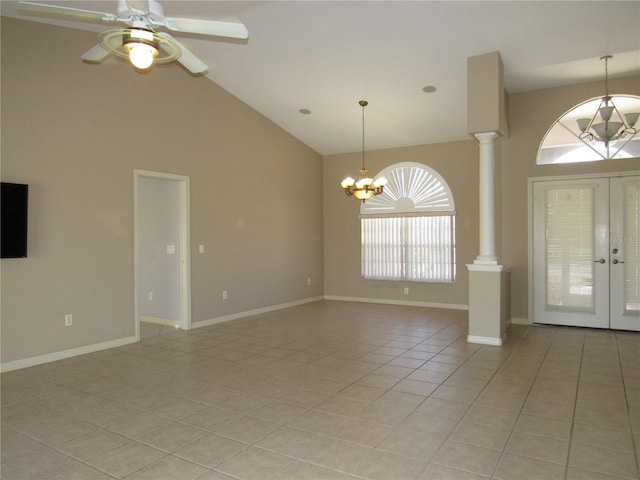 entrance foyer with ornate columns, french doors, light tile patterned floors, high vaulted ceiling, and ceiling fan with notable chandelier