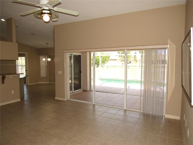 empty room with light tile patterned floors, baseboards, vaulted ceiling, and ceiling fan