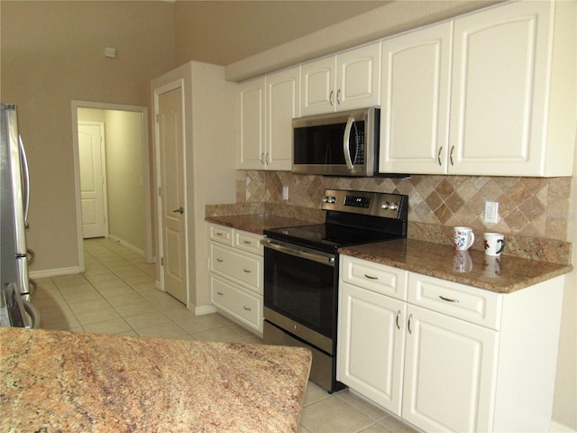 kitchen featuring decorative backsplash, light tile patterned flooring, appliances with stainless steel finishes, white cabinetry, and stone counters