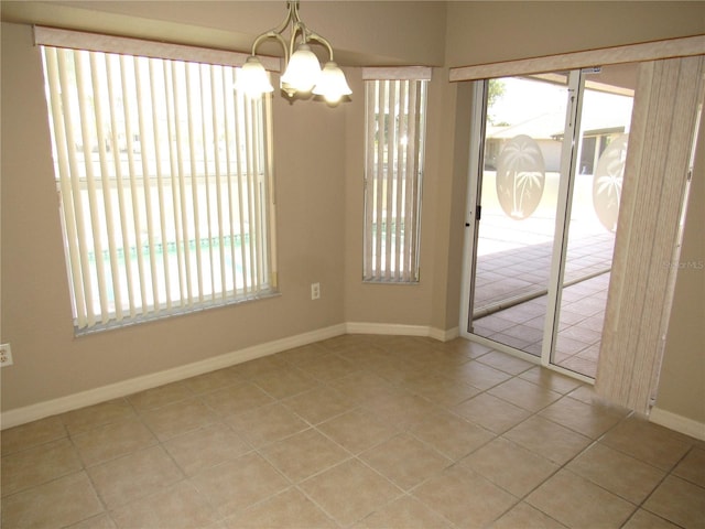 spare room featuring baseboards, light tile patterned floors, and a chandelier