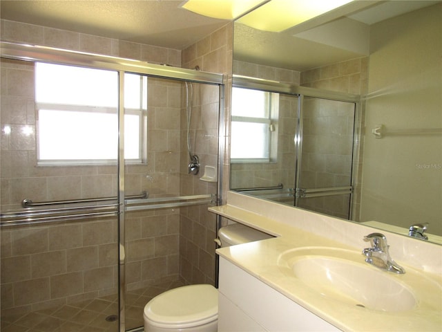 full bathroom featuring toilet, vanity, and a shower stall
