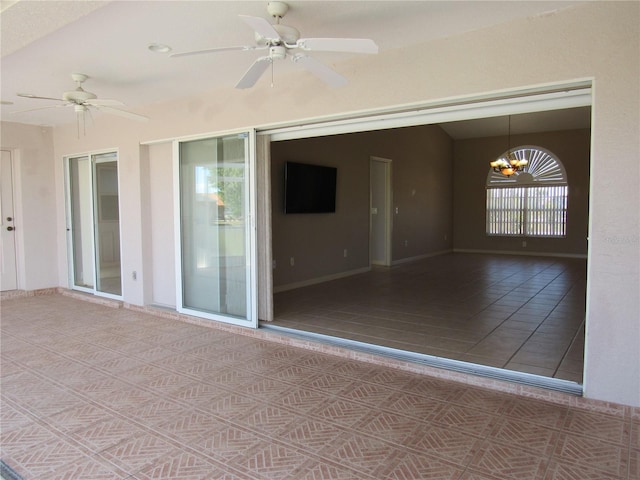 tiled empty room with ceiling fan with notable chandelier, baseboards, and vaulted ceiling