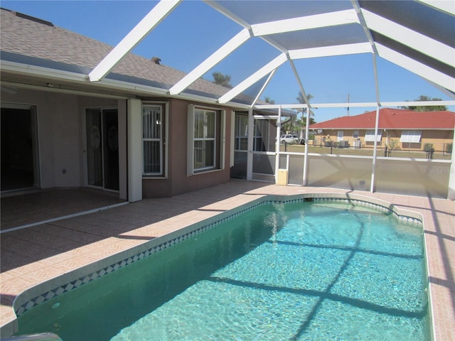 outdoor pool featuring glass enclosure and a patio area