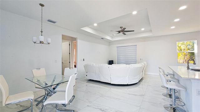 living area with recessed lighting, ceiling fan with notable chandelier, marble finish floor, a raised ceiling, and visible vents