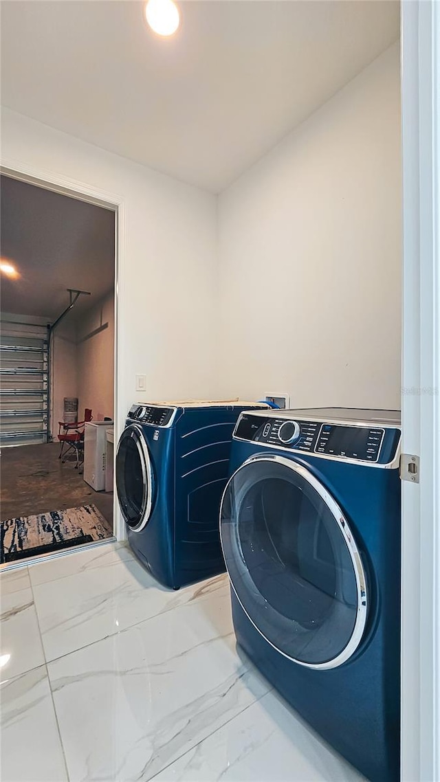 clothes washing area featuring marble finish floor, laundry area, and washer and clothes dryer