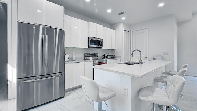 kitchen with visible vents, a breakfast bar, marble finish floor, stainless steel appliances, and a sink