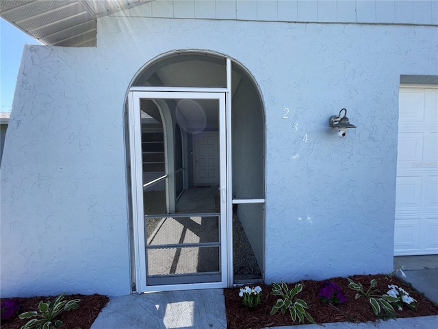 doorway to property featuring stucco siding and a garage
