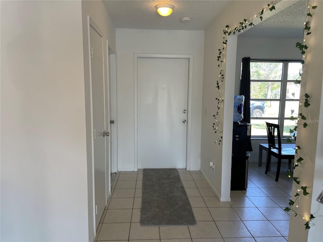 foyer with baseboards, light tile patterned floors, and a textured ceiling
