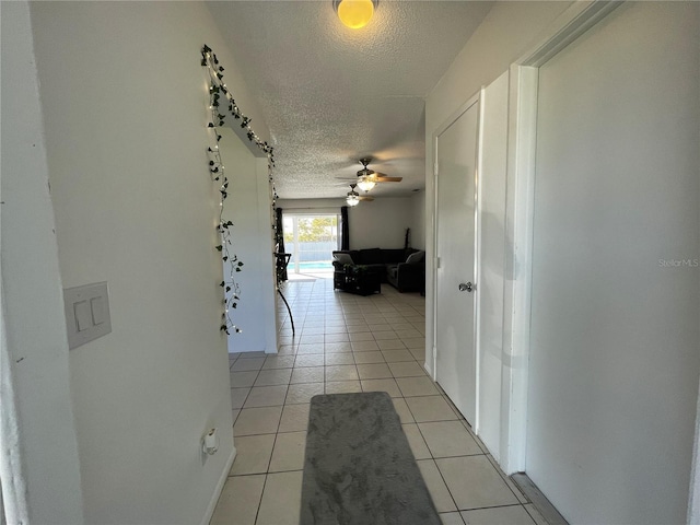 hall featuring light tile patterned flooring and a textured ceiling