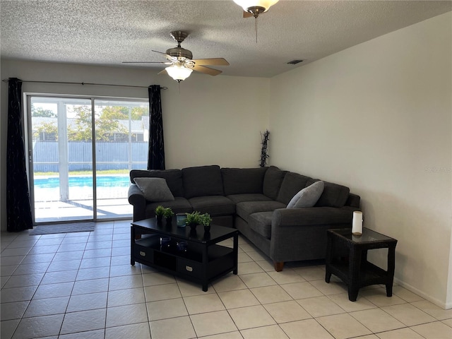 living room with light tile patterned flooring, a textured ceiling, ceiling fan, and visible vents