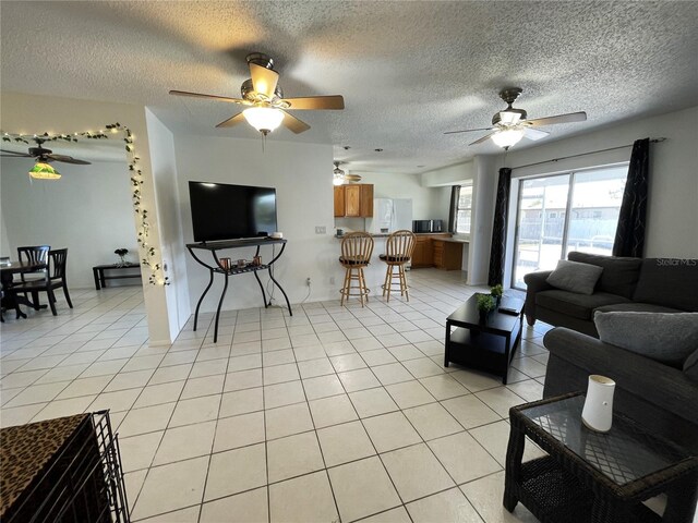 living area with a textured ceiling, light tile patterned floors, and a ceiling fan