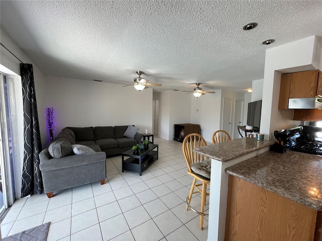 living area with a ceiling fan, light tile patterned flooring, and a textured ceiling