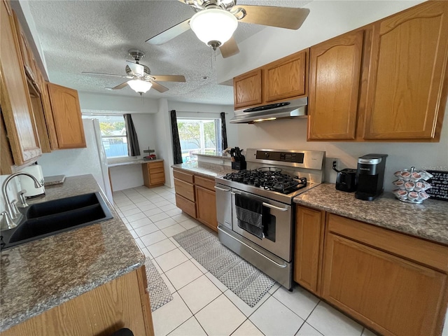 kitchen with a sink, a ceiling fan, a textured ceiling, under cabinet range hood, and stainless steel range with gas cooktop