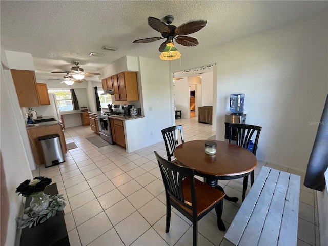 dining space featuring a textured ceiling, ceiling fan, visible vents, and light tile patterned floors
