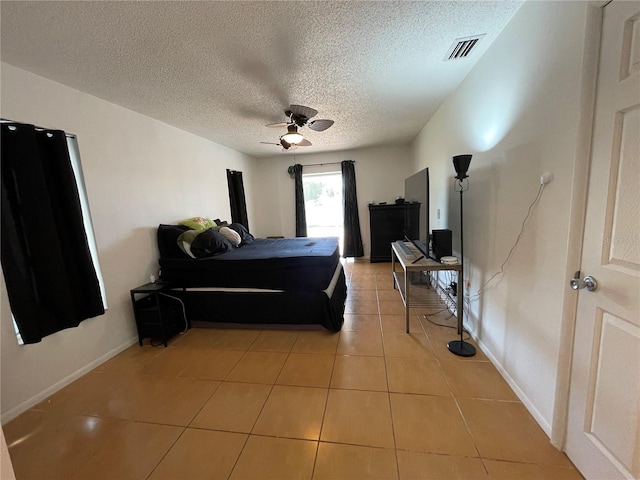 bedroom with light tile patterned flooring, a textured ceiling, baseboards, visible vents, and ceiling fan