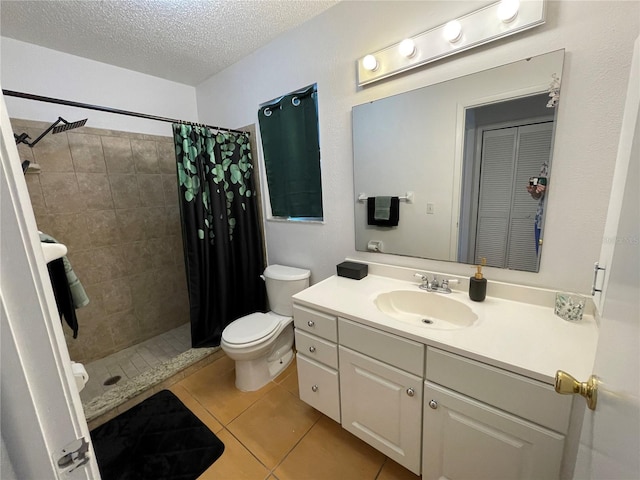 full bath featuring vanity, a tile shower, toilet, a textured ceiling, and tile patterned floors
