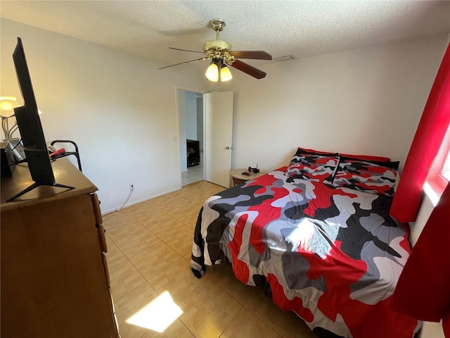 bedroom with light tile patterned floors, a textured ceiling, visible vents, and a ceiling fan