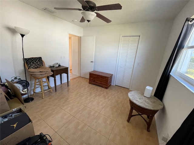 living area featuring a textured ceiling, visible vents, ceiling fan, and light tile patterned floors