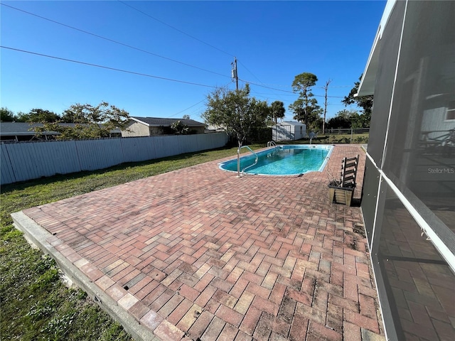 view of swimming pool featuring a patio, a fenced in pool, a fenced backyard, an outdoor structure, and a shed