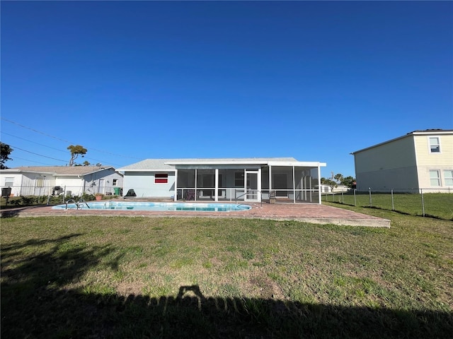 rear view of house with a lawn, a sunroom, fence, and a fenced in pool