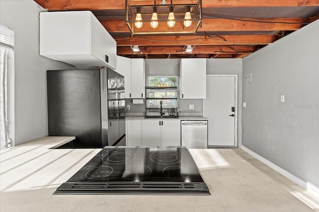 kitchen with white cabinets, light countertops, baseboards, appliances with stainless steel finishes, and a sink