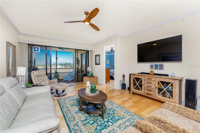 living room with baseboards, ornamental molding, light wood-style flooring, and ceiling fan
