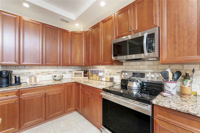kitchen with backsplash, light stone countertops, appliances with stainless steel finishes, and visible vents
