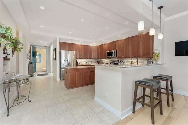 kitchen with light stone counters, stainless steel appliances, decorative light fixtures, a peninsula, and backsplash