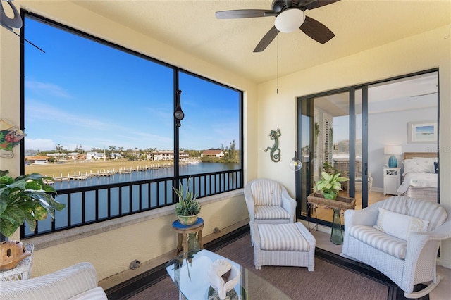sunroom / solarium with a water view and a ceiling fan
