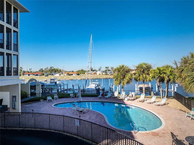 community pool featuring a water view, a patio area, and fence