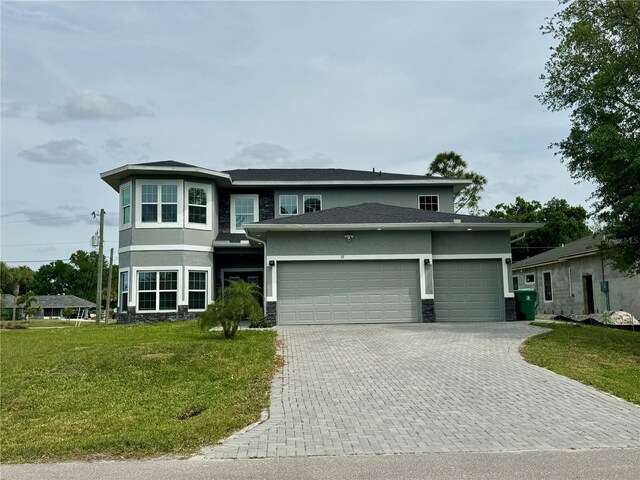 prairie-style house with stucco siding, an attached garage, stone siding, decorative driveway, and a front lawn