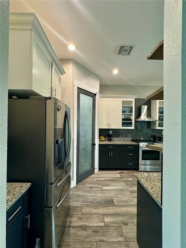 22223 Seyburn Ter, Port Charlotte, FL 33954 - kitchen featuring light wood-type flooring, backsplash, visible vents, wall chimney exhaust hood, and appliances with stainless steel finishes