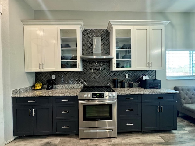 22223 Seyburn Ter, Port Charlotte, FL 33954 - kitchen with wall chimney range hood, tasteful backsplash, white cabinetry, and stainless steel range with electric cooktop