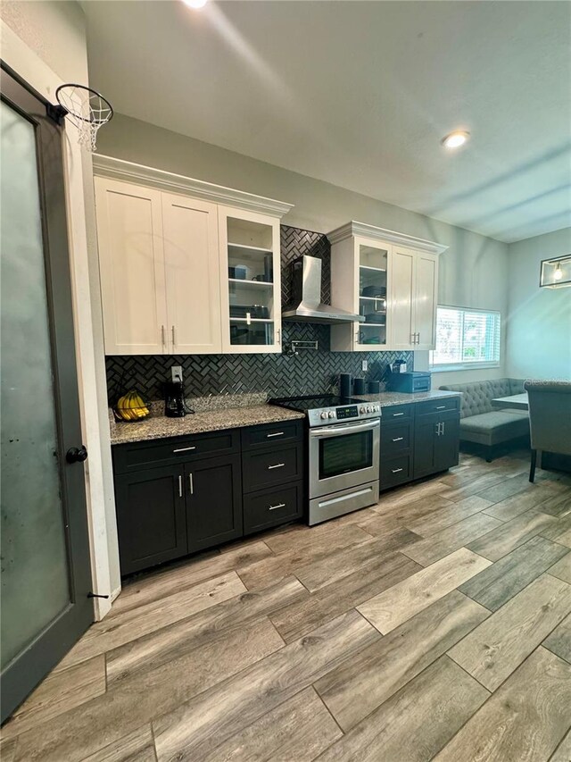 22223 Seyburn Ter, Port Charlotte, FL 33954 - kitchen featuring light wood-style flooring, wall chimney range hood, white cabinets, and electric range