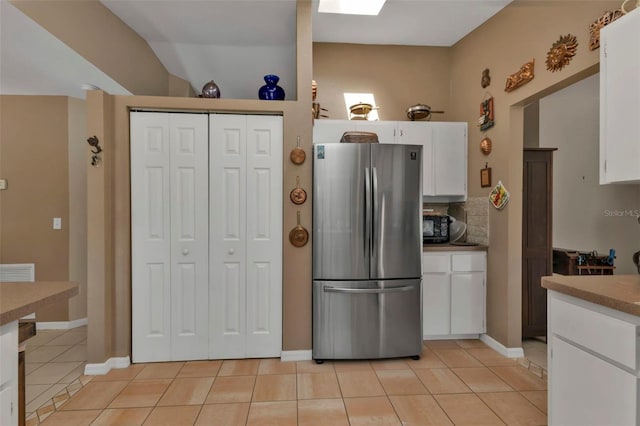 4420 Larkspur Ct, Port Charlotte, FL 33948 - kitchen featuring white cabinets, decorative backsplash, light tile patterned floors, and freestanding refrigerator