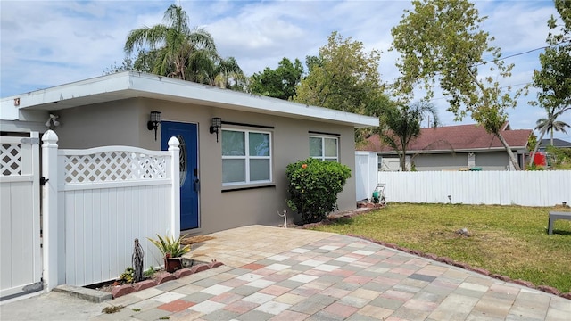 view of front of home featuring fence, a front lawn, a gate, and stucco siding