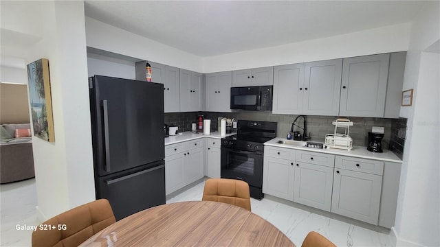 kitchen with light countertops, marble finish floor, black appliances, and tasteful backsplash