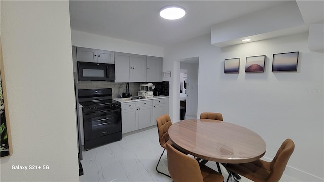 kitchen featuring tasteful backsplash, marble finish floor, gray cabinets, light countertops, and black appliances