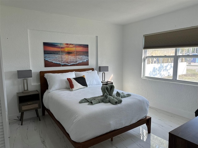 bedroom with a textured wall, marble finish floor, and baseboards