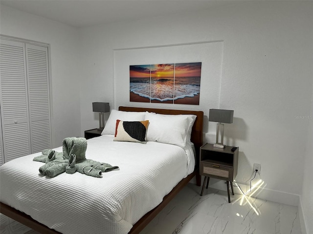 bedroom with baseboards, marble finish floor, and a closet