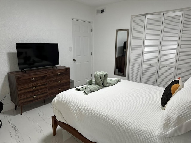 bedroom featuring a closet, marble finish floor, and visible vents