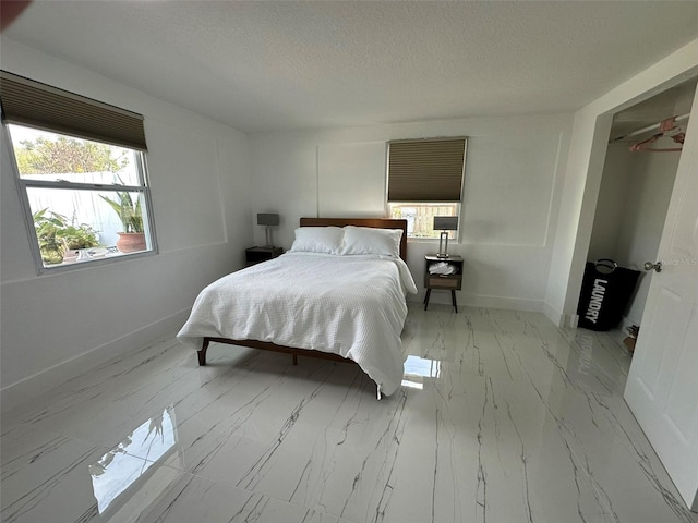 bedroom featuring baseboards, marble finish floor, and a textured ceiling