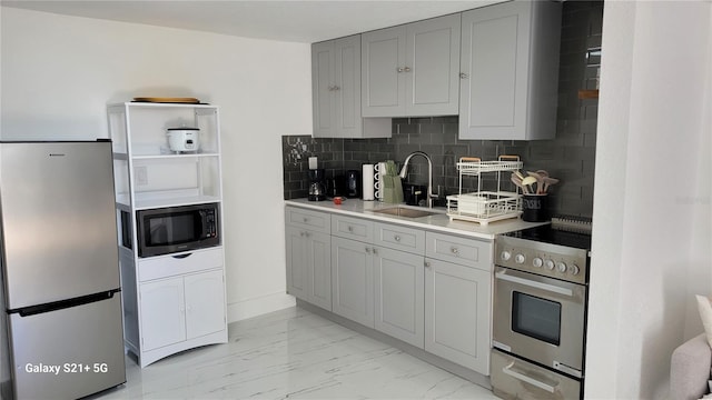 kitchen with stainless steel appliances, a sink, tasteful backsplash, marble finish floor, and light countertops