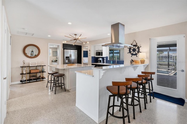280 Belvedere Ct, Punta Gorda, FL 33950 - kitchen featuring light speckled floor, appliances with stainless steel finishes, light countertops, island range hood, and a breakfast bar area