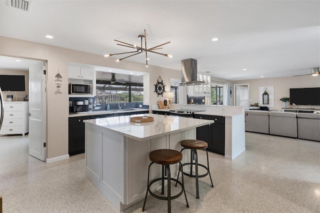 280 Belvedere Ct, Punta Gorda, FL 33950 - kitchen with visible vents, light speckled floor, black microwave, island range hood, and a kitchen island