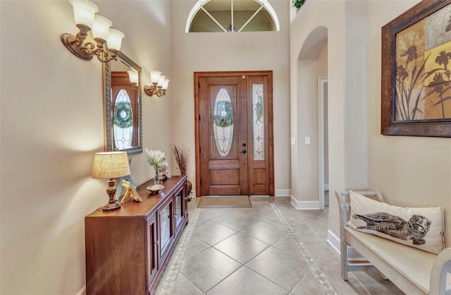 foyer entrance with baseboards, arched walkways, and light tile patterned floors