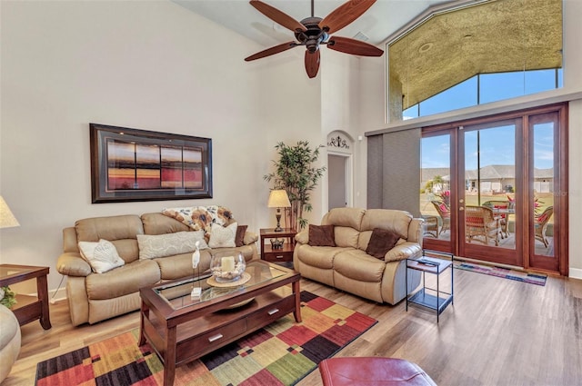 living area with wood finished floors, a towering ceiling, and a ceiling fan