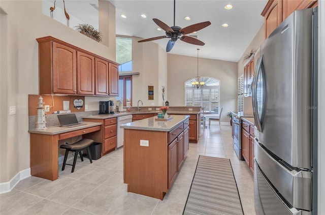 kitchen with stainless steel appliances, ceiling fan with notable chandelier, a sink, a peninsula, and brown cabinets