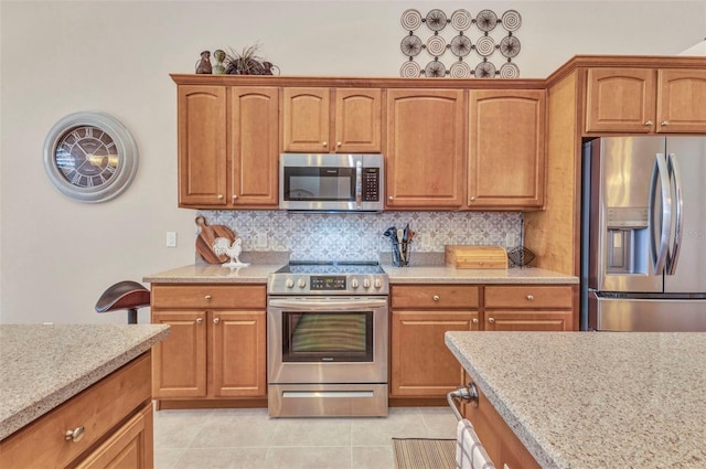 kitchen featuring decorative backsplash, brown cabinets, stainless steel appliances, and light tile patterned floors