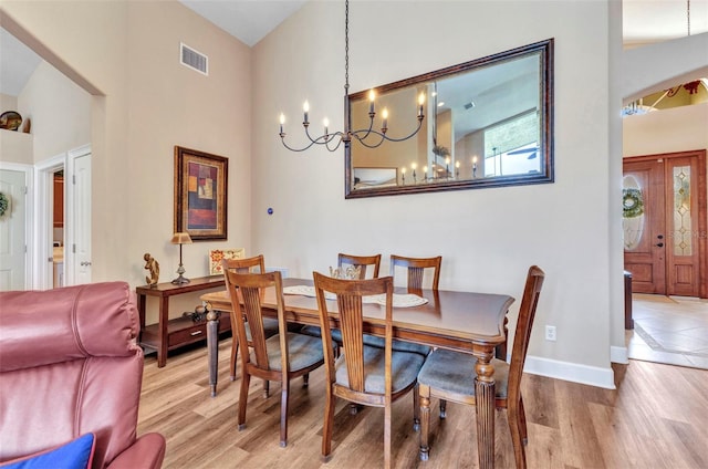 dining space with baseboards, visible vents, a notable chandelier, and wood finished floors